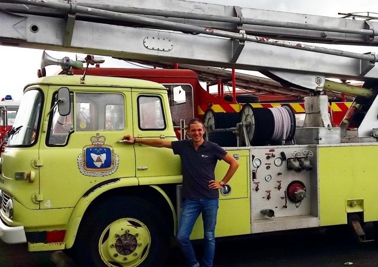 PhD student Billy Haworth with a retro fire tanker in Launceston, while on placement at Tasmania Fire Service