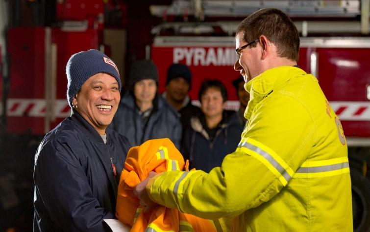 New volunteer receiving their uniform from a volunteer. Photo supplied by Country Fire Authority. 
