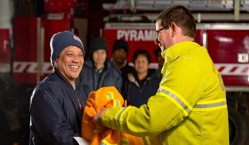 New volunteer receiving their uniform from a volunteer. Photo supplied by Country Fire Authority. 